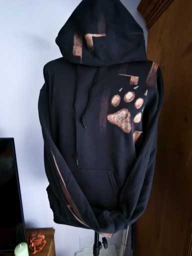 Hoodie mit Wolfskopf auf der Rückseite, vorne eine Wolfspfote. Graphischer Hintergrund, der sich auf dem Ärmel und der Kapuze wiederholt 