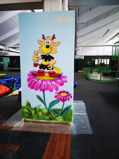 Bemalte Wand des Indoor Spielplatzes Wölpi. Maskottchen auf der Blume