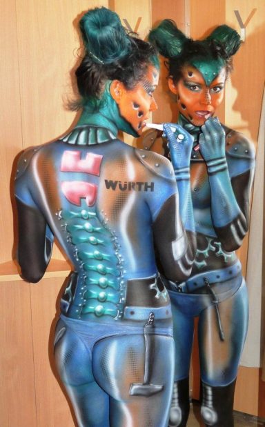 Bodypainting eines Roboters, welcher sich im Spiegel den Lippenstift nachzieht.