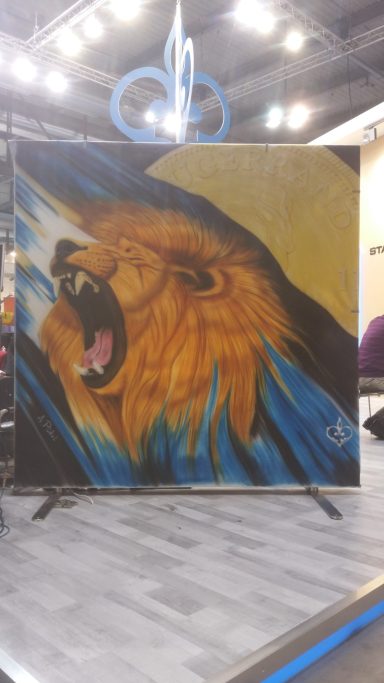 Südafrika Livebemalung einer 2x2m Leinwand.
Ein brüllenden Löwen mit einer Krügerrand Münze im Hintergrund